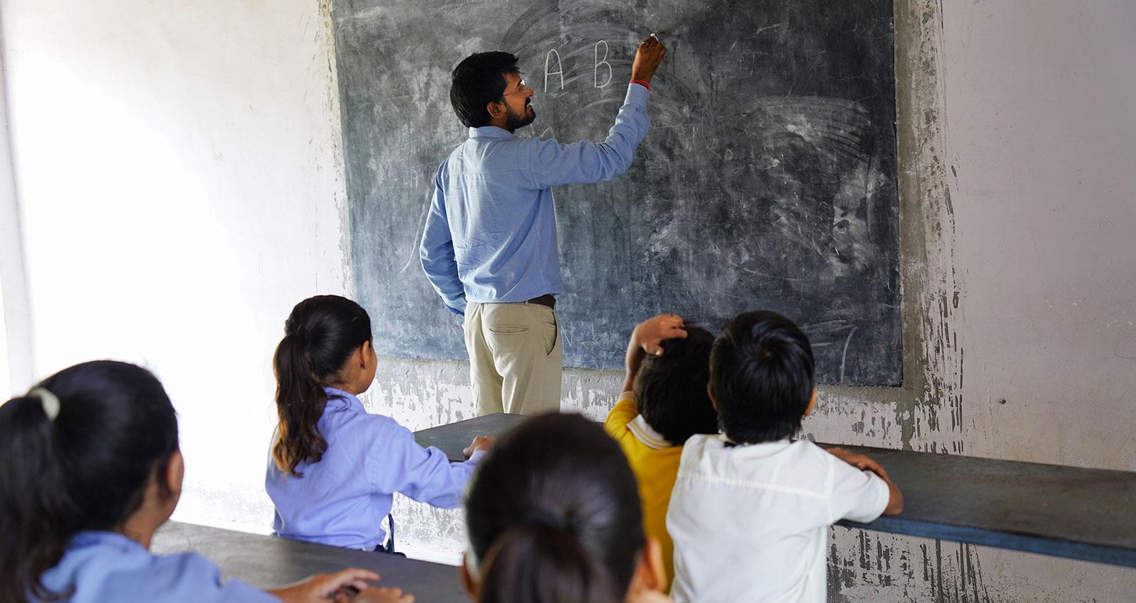 Indian teacher teaching to rural school student in classroom, Typical scene in a rural or small village school in India