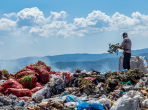 A view of garbage field in trash dump or open landfill, food and plastic waste products polluting in a trash dump, Workers hands sorting garbage for recycling.