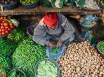 A man surrounded by vegetables and greens at his place at Indian Bazaar. A mix of colors and textures. Captured in India, Uttar Pradesh, Varanasi.